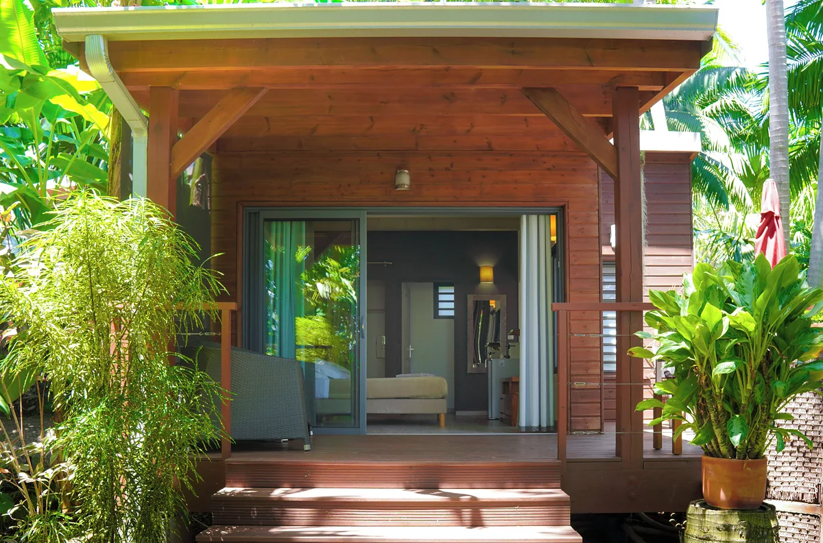 Un lodge en bois au milieu des plantes, sa baie ouverte sur la chambre